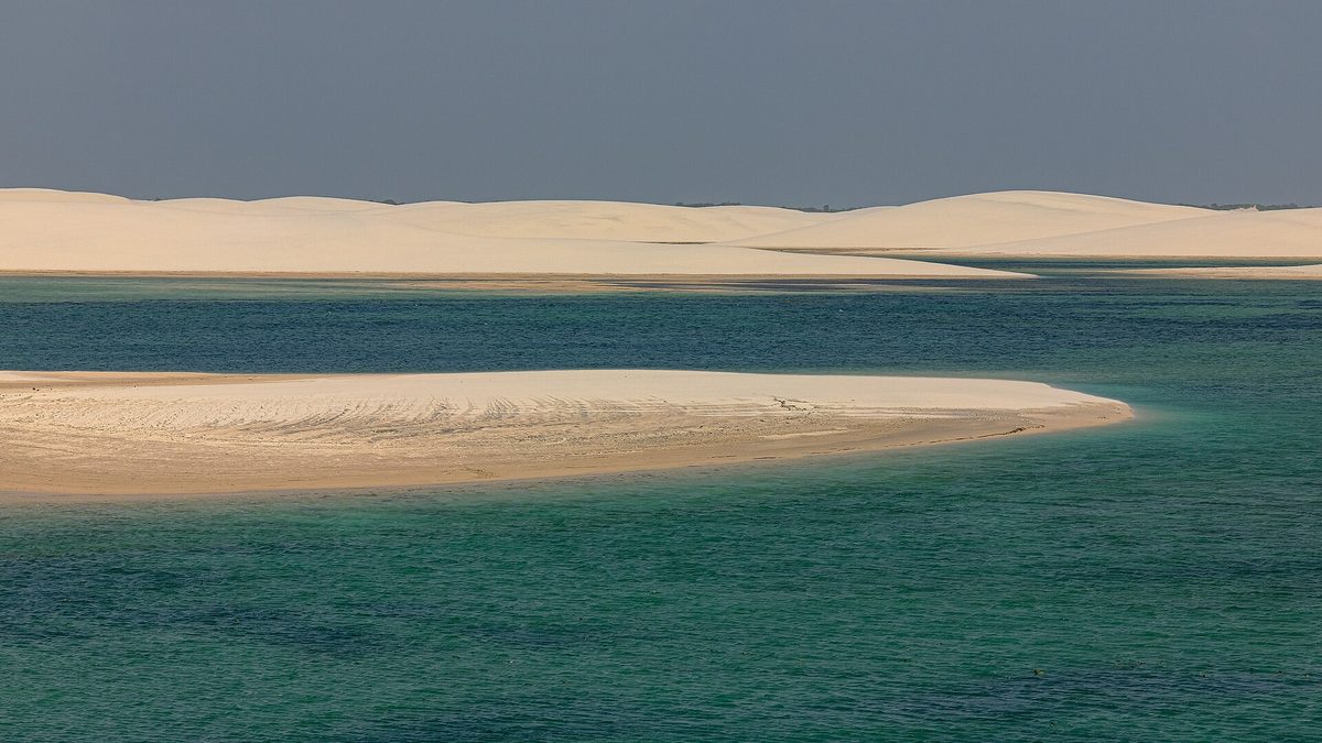 Lagoa de água esverdeada entre dunas de areia nos Lençóis Maranhenses