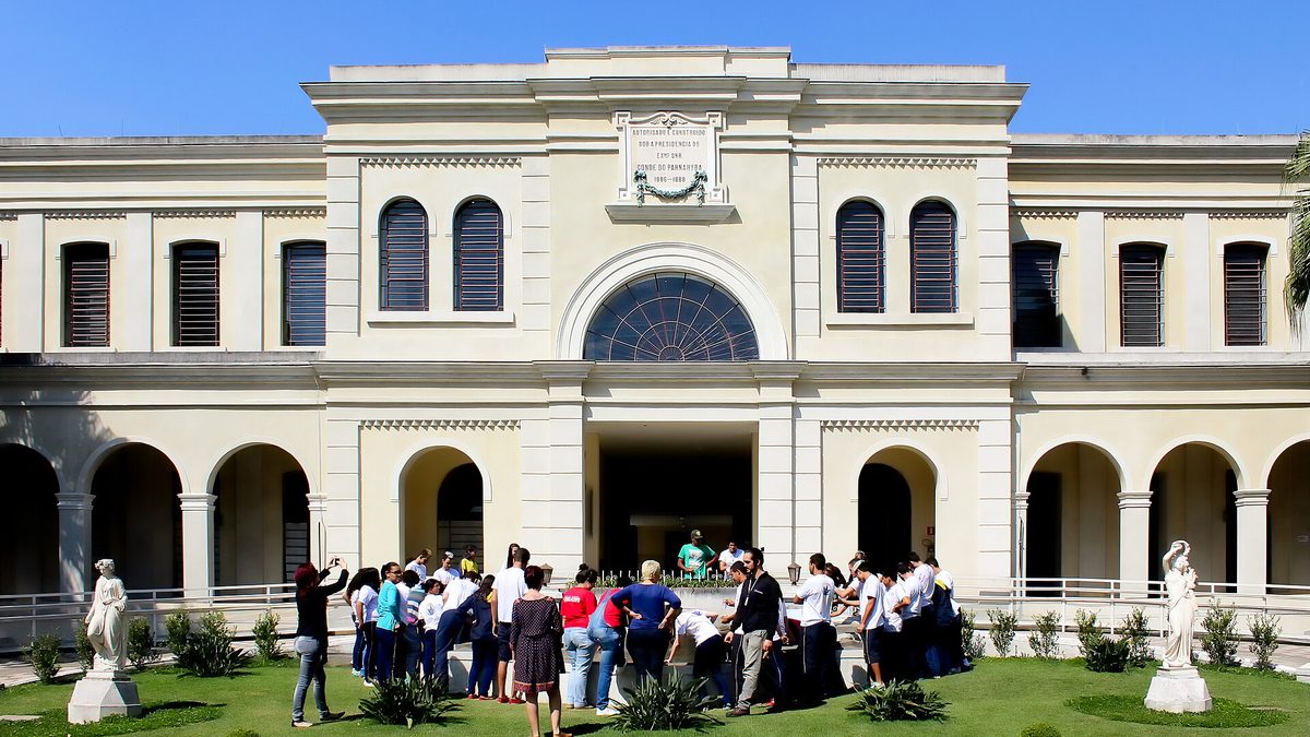 Fachada do Museu da Imigração, em São Paulo, com visitantes no jardim