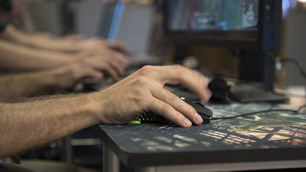 Mãos de jogador sobre teclado e mouse durante partida no computador