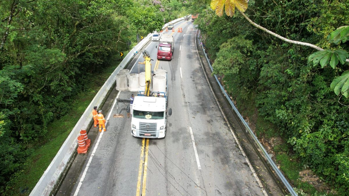Trecho de serra da rodovia Mogi-Bertioga, com caminhão e operários na pista