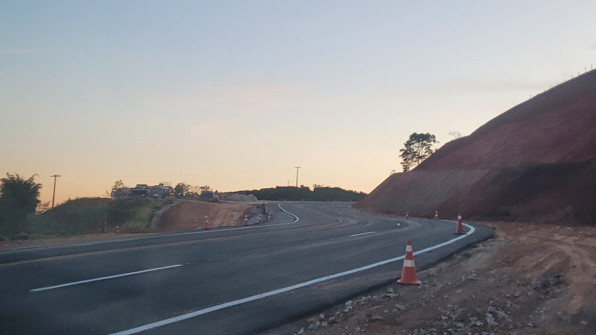 Trecho de serra da BR-459 ao entardecer, com pista nova e cones na lateral