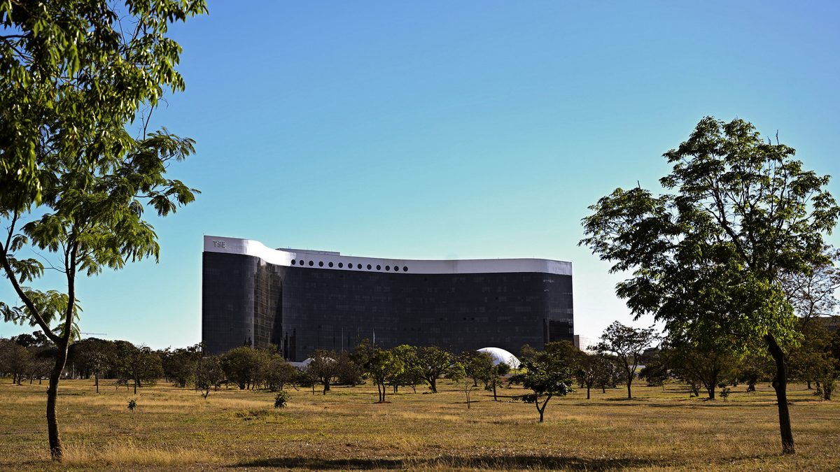 Sede do Tribunal Superior Eleitoral vista de longe, entre árvores do cerrado, em Brasília