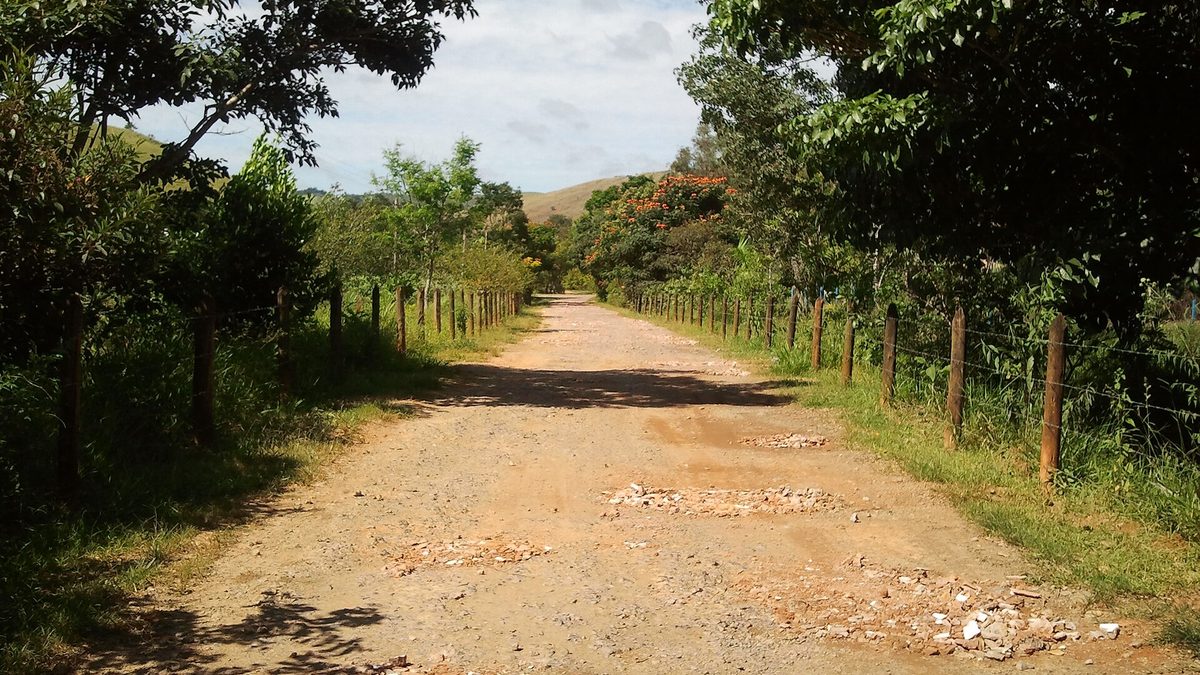 Estrada de terra entre cercas e árvores na zona rural de Valença, no Sul Fluminense
