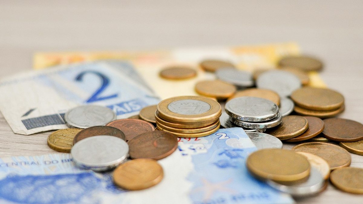 Moedas e cédulas de real sobre uma mesa
