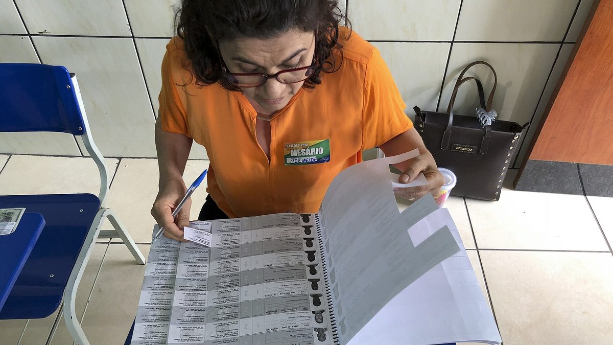 Mesária confere o caderno de votação em seção eleitoral