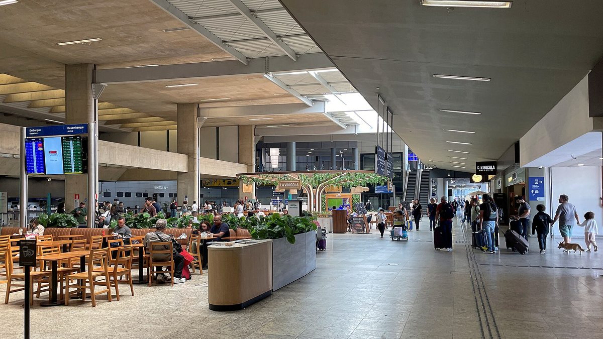 Saguão do Aeroporto Internacional de Belo Horizonte, em Confins, com passageiros e mesas